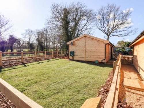 a large yard with a shed in the background at Clover Lodge in Leiston