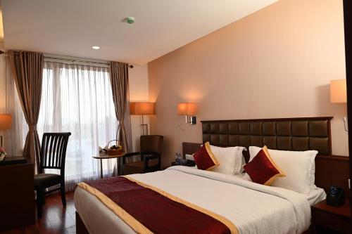 una camera d'albergo con un grande letto e una sedia di Raaj Bhaavan Clarks Inn Chennai a Chennai