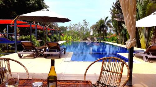 a bottle of wine sitting on a table next to a pool at Q Bungalows in Kep