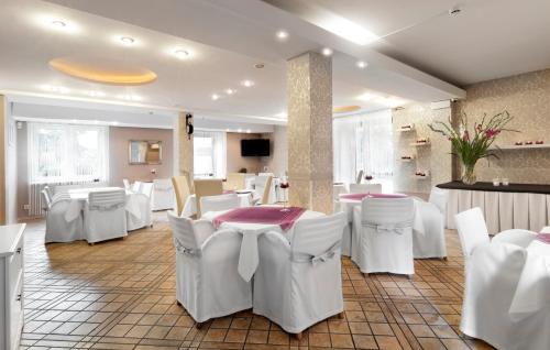 a restaurant with white tables and white chairs and a room at Hotel Petrus in Kraków