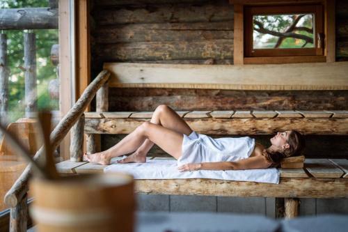 a woman laying on a bed in a log cabin at Residenz Royal in Gmünd
