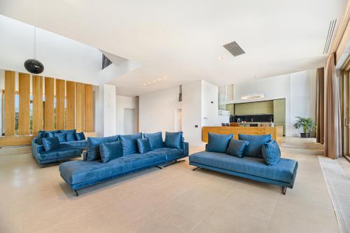 a living room with blue couches and a kitchen at Seascape Villa in Eforie Sud
