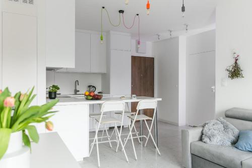 una cocina blanca con mesa y sillas en una habitación en Tree&Lake Apartament Warszawa en Ząbki