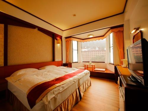um quarto com uma cama grande e uma televisão em Utopia Holiday Hotel em Heping