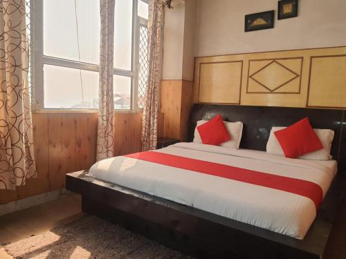 ein Schlafzimmer mit einem Bett mit roten und weißen Kissen in der Unterkunft East End in Shimla