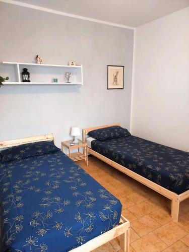 two beds in a room with blue sheets at Casa Edda in Malcesine