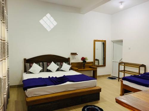 een slaapkamer met een bed met blauwe lakens en een spiegel bij Gimanhala Diyathalawa in Diyatalawa