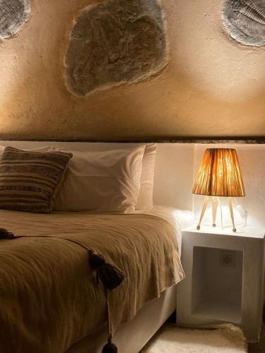 a bedroom with a bed with a lamp on a night stand at Manzil La Tortue in Douar Caïd Layadi