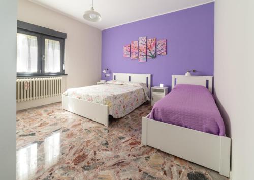 a bedroom with two beds and a purple wall at B&B A casa di Emy in Barisciano