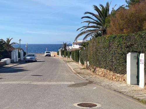 a car parked on the side of a road next to the ocean at Villa con piscina privada y gran jardín in Cala en Bosc