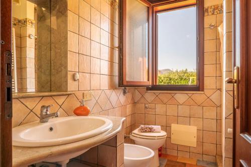 a bathroom with a sink and a toilet and a window at Villa Mafaradda a pochi passi dal Mare in Custonaci