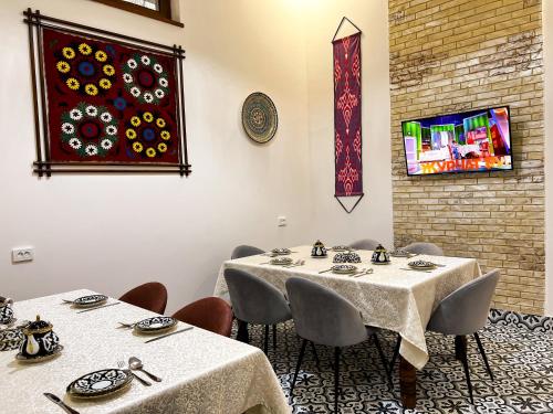 een eetkamer met twee tafels en een schilderij aan de muur bij Бутик-отель CHORBOG in Samarkand