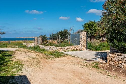 a dirt road with a fence and a stone wall at Villa Mafaradda a pochi passi dal Mare in Custonaci