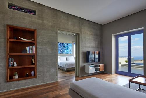 My Santorini Villa, Pyrgos Luxury في بيرغوس: غرفة نوم بسرير وتلفزيون ونافذة