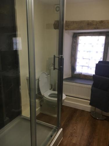 a bathroom with a toilet with a window and a glass door at Bank House | Peak District in Longnor