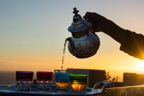a person holding a teapot with four glasses on a tray at NjoY Morocco in Tamraght Ouzdar