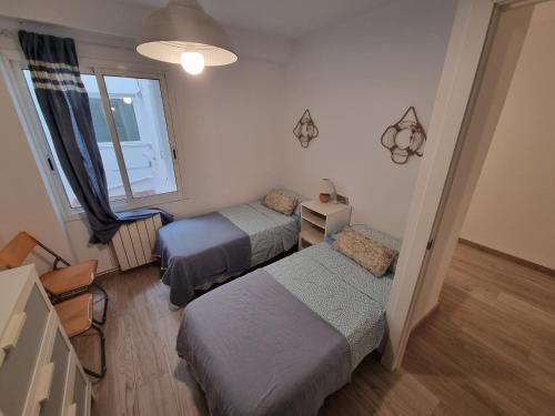 ein Schlafzimmer mit zwei Betten und einem Fenster in der Unterkunft APARTAMENTO PRIMERA LINEA MAR CAMBRILS cerca PUERTO in Cambrils