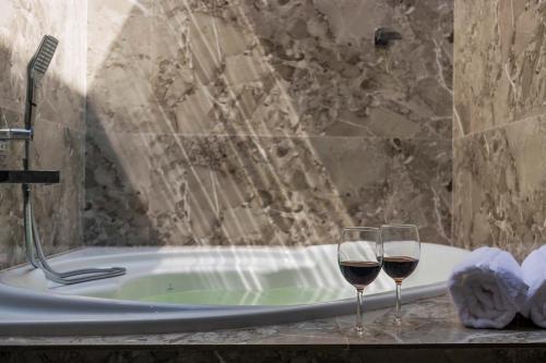 two glasses of wine sitting next to a bath tub at StayVista's Bellisimo Panorama - Lakeside Oasis with Infinity Pool, Modern Interiors, Open-to-Sky Bathtub, and Lush Green Lawn in Nashik