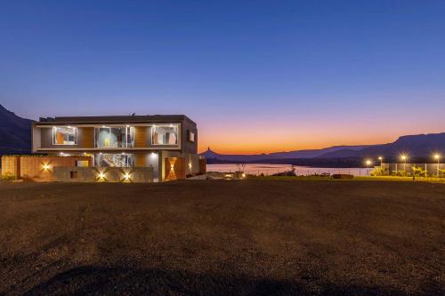 a house with the sunset in the background at StayVista's Bellisimo Panorama - Lakeside Oasis with Infinity Pool, Modern Interiors, Open-to-Sky Bathtub, and Lush Green Lawn in Nashik
