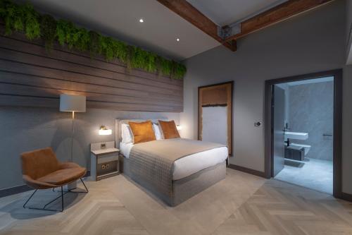 a bedroom with a bed and a chair and a bathroom at The Heyford Hotel in Upper Heyford