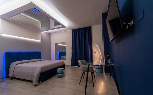 1 dormitorio con 1 cama, escritorio y TV en Intimity Luxury Rooms, en Qualiano