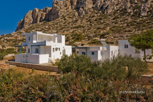 a group of white houses in front of a mountain at Albatros Studios & Apartments in Lefkos Karpathou