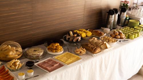 a table filled with different types of bread and pastries at Pousada Buriti in Itaúnas