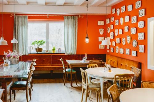 ein Restaurant mit orangefarbenen Wänden, Tischen und Stühlen in der Unterkunft Das Franzl - Bett & Brot in St. Wolfgang