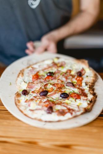 a pizza sitting on top of a plate on a table at Das Franzl - Bett & Brot in St. Wolfgang