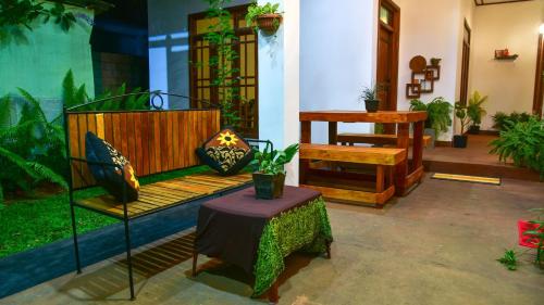 a room with a bench and a table with potted plants at Menara Green Inn in Dambulla