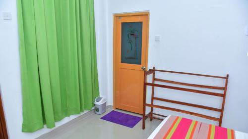 a room with green curtains and a door and a bed at Menara Green Inn in Dambulla