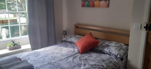 a bedroom with a bed with a orange pillow on it at Penbetha House B&B in Truro