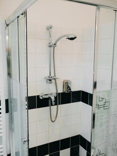 a shower in a bathroom with black and white tiles at Vila Na Landeku in Ostrava