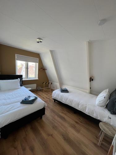 two beds in a room with wooden floors at Mid83 in Woudsend