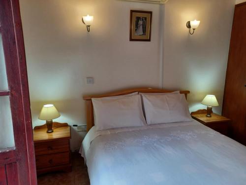1 dormitorio con 1 cama blanca y 2 mesitas de noche con lámparas en Niovi House, en Tochni