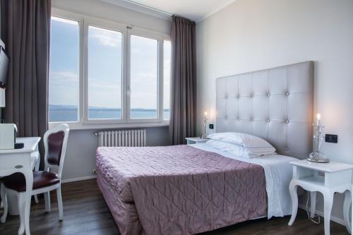 a bedroom with a large bed with a large window at Hotel Degli Oleandri in Sirmione