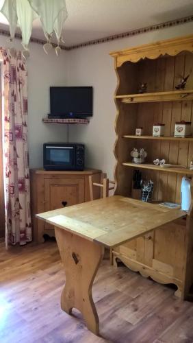 Cette chambre comprend une grande table en bois et une télévision. dans l'établissement APPARTEMENT PRAZ VILLAGE, à Praz-sur-Arly