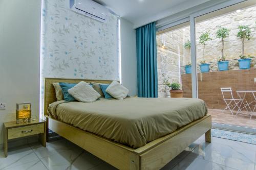 a bedroom with a bed and a large window at Ta' Ġilard - Lovely Renovated Holiday Home in Żabbar