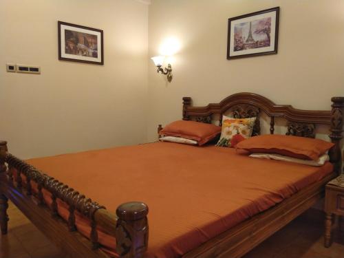 una camera da letto con un grande letto in legno con cuscini arancioni di Haven Amidst Nature in Villa Palmas, Arpora a Goa Velha