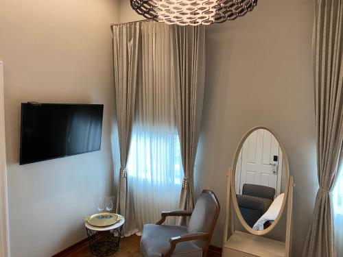 a room with a mirror and a chair and a television at Villa Promenade in Burgas City