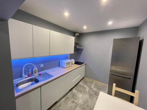 cocina con armarios blancos, fregadero y nevera en Good Rooms Apartamenty z 3 sypialniami parking, en Łódź