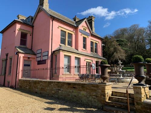 uma casa cor-de-rosa com uma vedação à frente. em Vale House em Belvoir