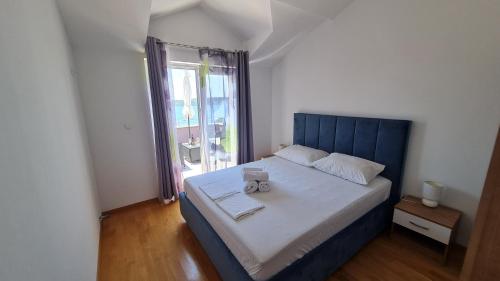 een slaapkamer met een bed met een blauw hoofdeinde en een raam bij Apartmani Ferdi in Trogir