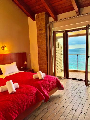 a bedroom with a red bed with a view of the ocean at Entheon Rooms in Marathopolis