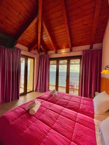 a bedroom with a large pink bed with a view of the ocean at Entheon Rooms in Marathopolis