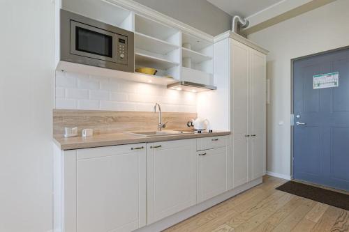 een witte keuken met een wastafel en een magnetron bij City Center Studio Apartment in Tallinn