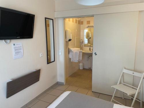 a bathroom with a television on the wall and a bathroom with a sink at Hôtel de la Plage in Houlgate