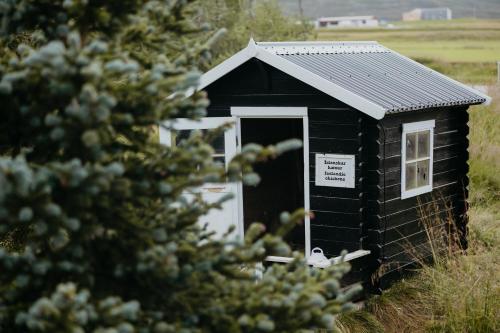 a black outhouse with a window and a pine tree at Brúnastaðir Holiday Home in Barð