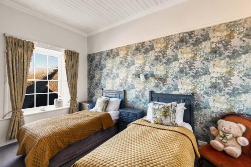 a bedroom with two beds and a teddy bear at Granville House Apartments and Garden Suites in Ballyferriter
