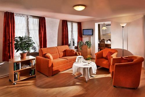 a living room with two orange couches and a table at Ferienwohnungen Hotel Eden Spiez in Spiez